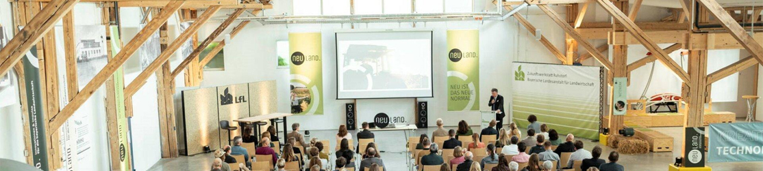 Publikum in bestuhlter Halle mit Großleinwand