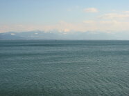 Panoramaansicht über den Bodensee. Im Hintergrund ist eine Bergkette der Alpen sichtbar.