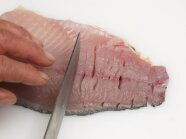 In einem Karpfen-Filet werden die Gräten eingeschnitten.