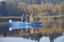Drei Personen stehen in einem blauen Boot auf dem Deixelfurter See.