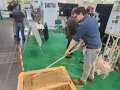 An einem Messestand recht ein Mann in einem Sandkasten.