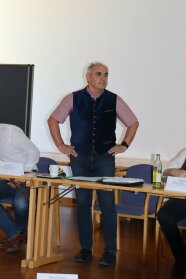 Ein Mann steht hinter einem Tisch.