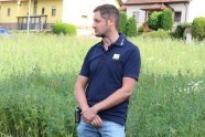 Eine Person am Rand eines Lupinenfeldes, im Hintergrund Häuser