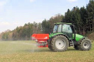 Traktor mit Schleuderstreuer auf dem Feld.