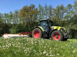 Traktor und Heckmähwerk beim Mähen einer Wiese