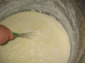 Hand rührt Milch in einem Einmer