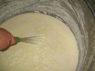 Person rührt Joghurt in großem Eimer