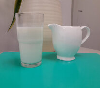 Glas Milch mit Kännchen auf dem Tisch