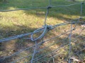 Mit einer Drahtschlinge lässt sich die Schürze am bestehenden Zaun befestigen.