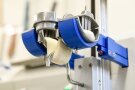 Der Blick von unten nach oben zeigt eine Apparatur, in der Teig auf blauen Plastik-Halbkreisen aufliegt und von oben mit Metallfüsschen fixiert wird. So eingespannt, wird der Teig mittig von einem Metallhaken nach unten gedrückt. (Foto: Tobias Hase, StmELF)e Art