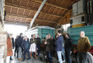 In der Maschinenhalle des Landwirts Beck stehen interessierte Teilnehmerinnen und Teilnehmer um Landwirt Josef Beck und lauschen seinen Ausführungen.