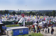 Jede Menge bunte Beachflags recken sich zwischen dicht gestellten Ausstellerzelten und landwirtschaftlichem Gerät in den Himmel.