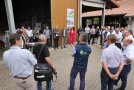 Eine Runde von Teilnehmern steht im Kreis vor dem Stall und hört dem Redner zu. 