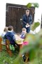 Der LfL-Präsident Stephan Sedlmayer steht vor einer Gruppe Kinder, die draußen an einem Tisch sitzen und erklärt ihnen Wissenswertes zum Thema Streuobst.