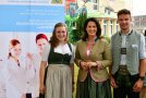 Die Ministerin mit zwei jungen Leuten vor einem Roll-up
