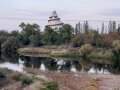 Hinter stehendem Gewässer und abwechslungsreicher Vegetation an Land ragt im Hintergrund ein weißer, kegelförmiger Turm mit grauer, nach oben umwindender Treppe in den Himmel. (Quelle: LfL) 