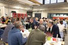 Viele Personen sitzen in einer Halle beim Mittagessen