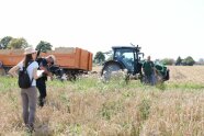 Drei Personen stehen auf einem Feld, ein Mann filmt mit einer Kamera