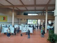 Viele Menschen in einem Foyer mit Posterständern, sie unterhalten sich