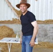 Ein Mann mit Hut steht in einem landwirtschaftlichen Arbeitsgebäude