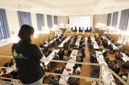 Blick von oben über den Saal auf die Bühne der Alten Reithalle. Dort diskutieren fünf Personen.