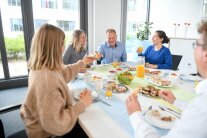 Personen sitzen beim Essen an einem gedeckten Tisch.