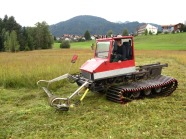 Ein Mann fährt mit einem Traktor mit Schneidewerk über eine Wiese