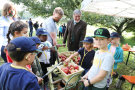 Schulkinder um eine Apfelpresse herum zum Apfelsaft pressen