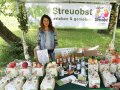 Frau an einem Ausstellungstand mit Streuobstprodukten im Grünen.