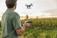 Drohne gesteuert von einem Mensch über einem Acker