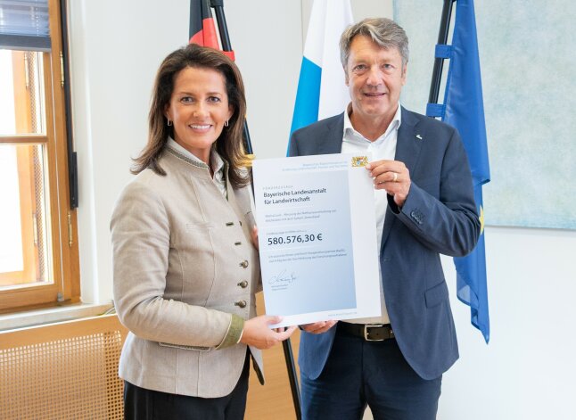 Zwei Personen halten eine Urkunde in Händen. 