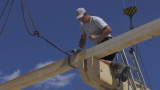 Person bohrt an einem Holzbalken