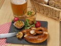 Brotzeit mit Breze und Obazda sowie Bierglas im Hintergrund