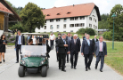 Viele Männer und Frauen in schicker Kleidung laufen auf einem Weg, im Hintergrund ein Gebäude 