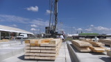 Kran hebt Holzbalken auf einen Betonboden