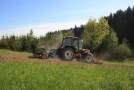 Traktor säht in einem Teilbereich einer Wiese Samen aus