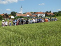 Besuchergruppe am Feld, im Hintergrund ein Dorf