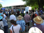 Begrüßungsrede vor einer großen Besuchergruppe vor landwirtschaftlichen Hallen