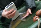 Ein Messgerät wird an einen lebenden Karpfen im Wasser gehalten. 