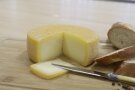 Eine abgeschnittene Scheibe Käse liegt neben einem großen Käsestück.