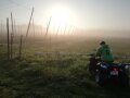 Ein Mann sitzt auf einem landwirtschaftlichen Fahrzeug und fährt über ein Feld. 